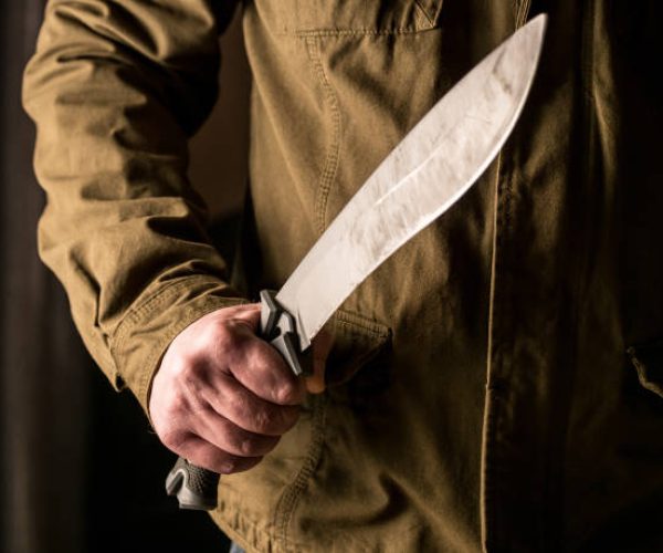 Man holding a machete in his and in a threatening stance