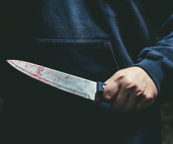 A man with a bloody knife in his hand close up.