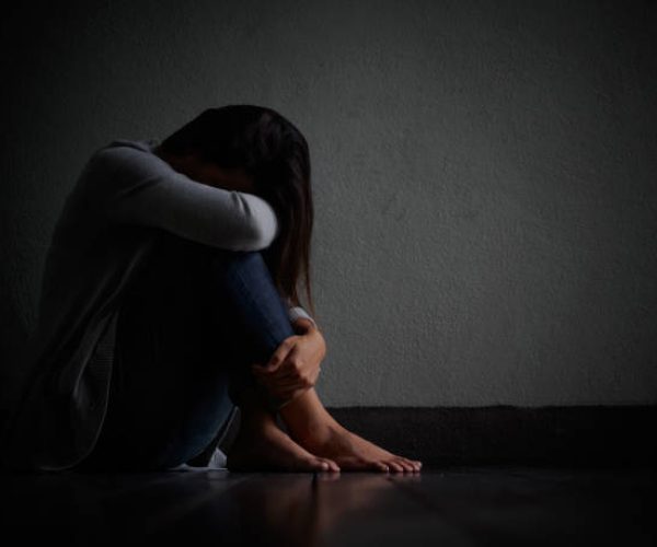 sad woman hug her knee and cry. Sad woman sitting alone in a empty room.