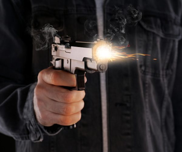 Man shooting handgun on black background, closeup
