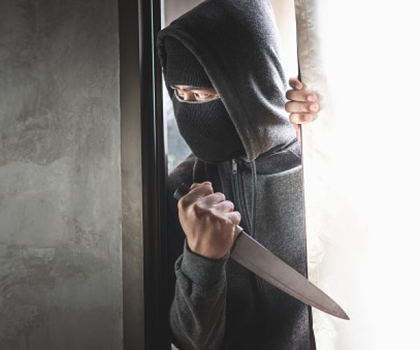 The thief holds a knife to open the house door for robbery.