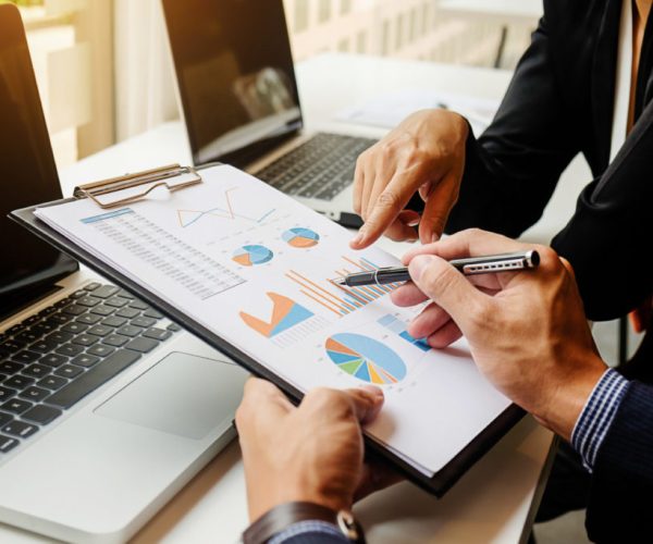 Business concept. Business people discussing the charts and graphs showing the results of their successful teamwork. Selective focus.